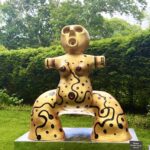 Abstract painted yellow sculpture of seated figure