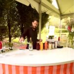 Bartender pouring drink at outdoor tent bar