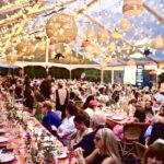 Crowded outdoor banquet under string lights
