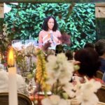 Woman speaking on stage at floral event
