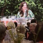 Smiling woman speaking at floral-decorated banquet