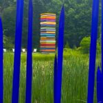 Blue glass rods framing colorful stacked sculpture
