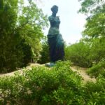 Classical draped statue amid lush garden