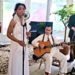 Singer and guitarist performing inside white tent